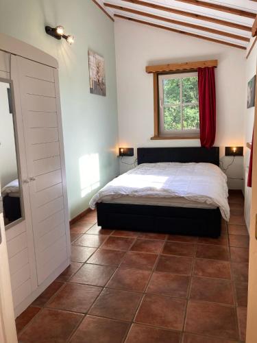 a bedroom with a bed and a window and a tiled floor at De Bedstee in Schoondijke