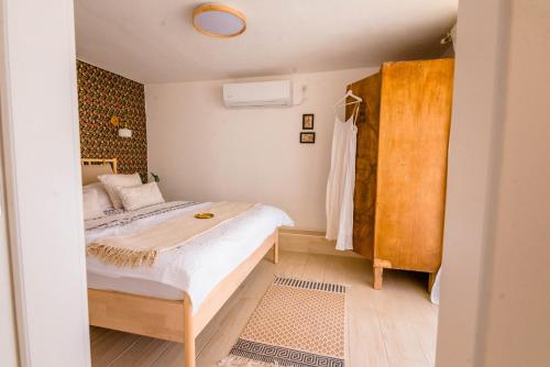 a small bedroom with a bed and a wooden cabinet at Cactus - צימר במדבר in Arad