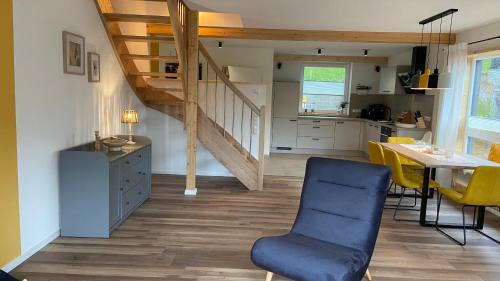 a kitchen and dining room with a blue chair and a staircase at Urlaub am Schwarzbach mit Sauna und Whirlpool Haus Felix in Küchelscheid