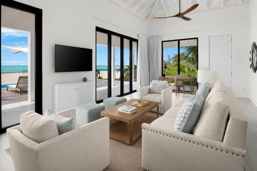 a living room with white furniture and a view of the ocean at Ambergris Cay - Private Island All-Inclusive in Big Ambergris Cay