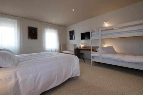 a bedroom with a white bed and bunk beds at Hôtel Les Pins in Saint-Trojan-les-Bains