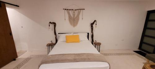 Dormitorio pequeño con cama con almohada amarilla en Pakáal Muliix - Limóm en Mérida
