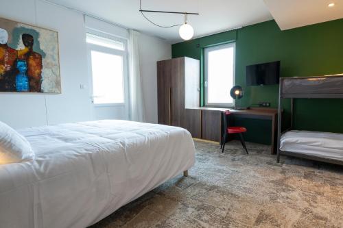 a bedroom with a bed and a desk with a television at Hôtel Les Pins in Saint-Trojan-les-Bains