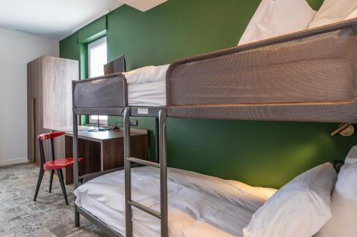 two bunk beds in a room with a green wall at Hôtel Les Pins in Saint-Trojan-les-Bains