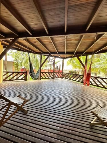 a wooden deck with two chairs and a hammock at Pousada Vento do Kite in Barra Grande