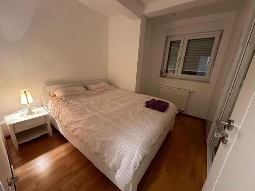 a small bedroom with a bed and a window at Apartman Pionirska dolina in Sarajevo