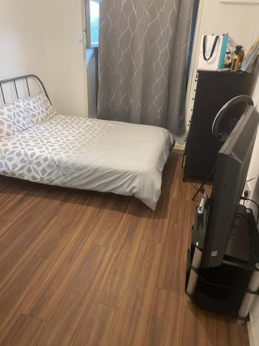 a bedroom with a bed and a tv and a wooden floor at Jah lodge in Croydon