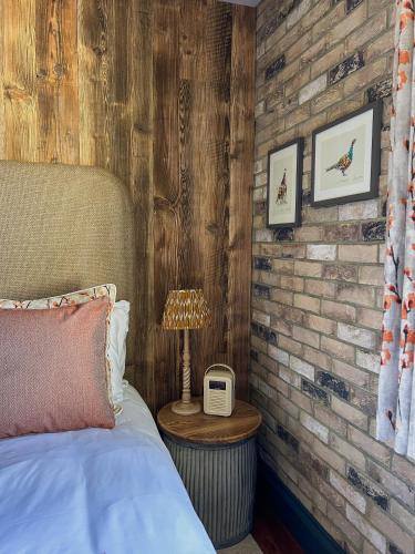 um quarto com uma parede de tijolos, uma cama e um candeeiro. em The Fitz Farmhouse em Swynnerton