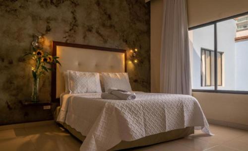 a bedroom with a white bed with a window at Hotel Virrey Cartagena in Cartagena de Indias
