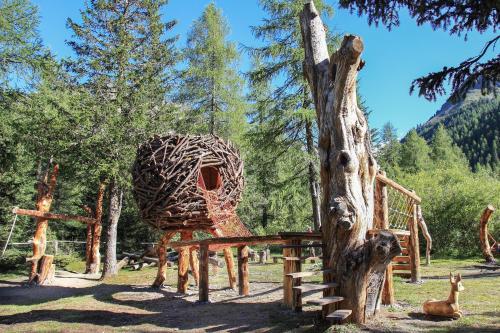 a wooden playground with a giraffe house next to a tree at Alpinchalet Ortler in Solda