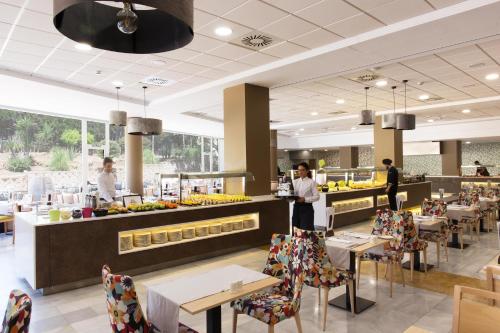 a restaurant with tables and chairs and people preparing food at ALEGRIA Costa Ballena Aquafun & Spa in Costa Ballena