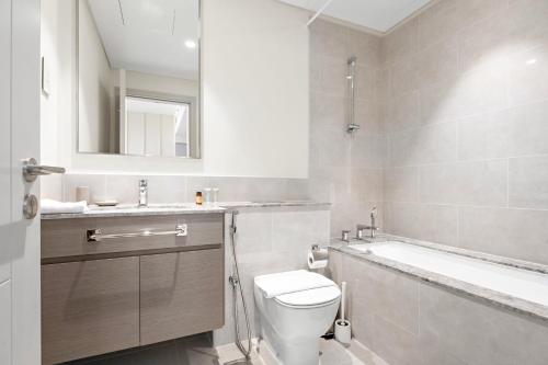 a bathroom with a toilet and a sink and a bath tub at Silkhaus Chic 1 BDR In a New Tower In Downtown in Dubai