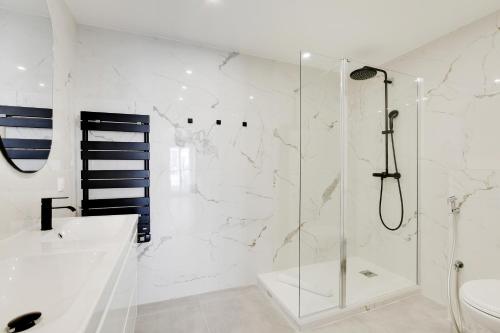 une salle de bain blanche avec une douche et un lavabo dans l'établissement Pick A Flat's Apartment in Grands-Boulevards - Boulevard Saint-Denis, à Paris