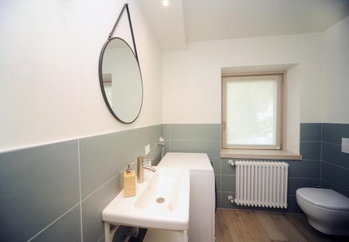 y baño con lavabo, espejo y aseo. en Appartamento Cembro, en Ossana