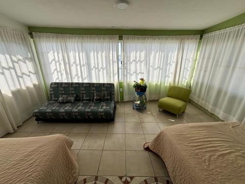 a living room with a couch and a green chair at Terraza del Lago in Tequesquitengo