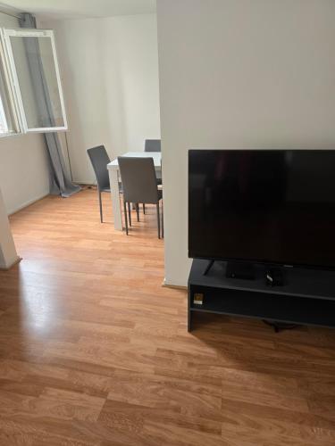 ein Wohnzimmer mit einem TV und einem Tisch mit Stühlen in der Unterkunft 10min from Paris 3 bedrooms parking in Asnières-sur-Seine