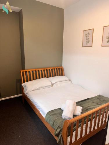 1 dormitorio con cama de madera con sábanas blancas en Milton Road Flat 1 - TSAC, en Hartlepool