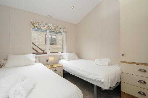 a bedroom with two beds and a window at Lodge 69 at Riviera Bay Coastal Retreat in Brixham
