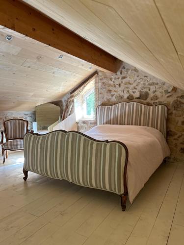 een slaapkamer met een groot bed in een stenen muur bij Au cœur du jardin in Souvigné