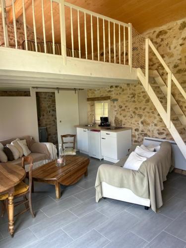een woonkamer met een loft met een bank en een tafel bij Au cœur du jardin in Souvigné