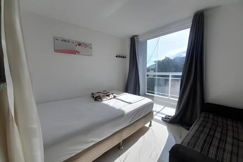 uma cama num quarto com uma grande janela em lindo apartamento no recreio bem pertinho da praia no Rio de Janeiro