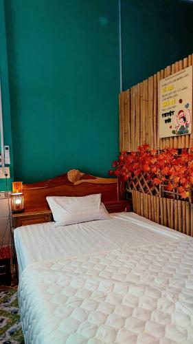 a bedroom with a large white bed with a green wall at Can Tho Farmstay in Cái Răng