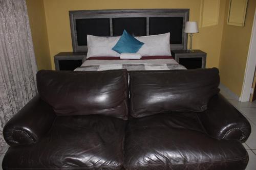 a brown leather couch sitting in front of a bed at DreamWest Living The Guesthouse in Krugersdorp