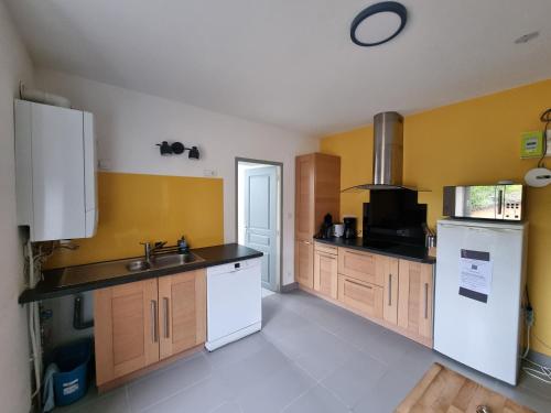 - une cuisine avec des murs jaunes et des appareils blancs dans l'établissement Le Tournesol, Appartement T1 bis, à Héricourt