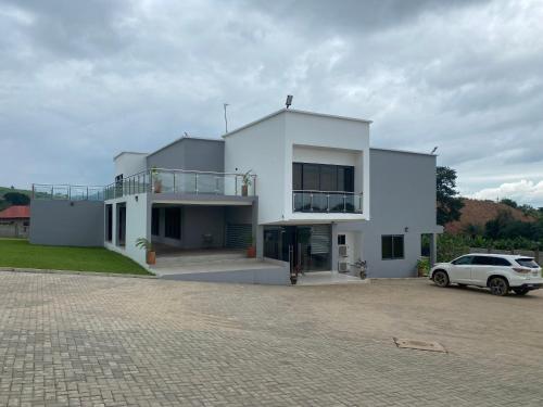 a white house with a car parked in front of it at Krotia Lodge Atimpoku in Atimpoko