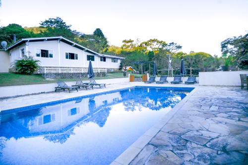 uma piscina com cadeiras e uma casa em Pousada Highland em Santo Antônio do Pinhal