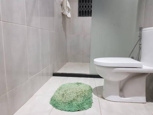 een badkamer met een toilet en een groen tapijt op de vloer bij Krotia Lodge Atimpoku 
