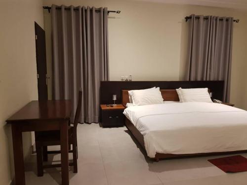 a bedroom with a bed and a table and a desk at Krotia Lodge Atimpoku 