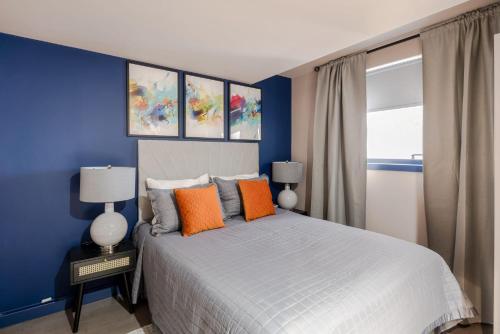 um quarto azul com uma cama com almofadas laranja em Urban Joy - Holborn By Frankie Says em Londres