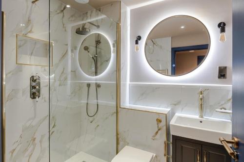 uma casa de banho com um chuveiro, um lavatório e um espelho. em Urban Joy - Holborn By Frankie Says em Londres