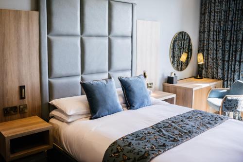 a bedroom with a large bed with blue pillows at Clifton Arms Hotel in Lytham St Annes