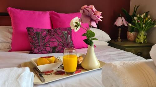 a tray of fruit and orange juice on a bed at Sticky Wicket by Spires Accommodation a comfortable place to stay in Swadlincote in Church Gresley