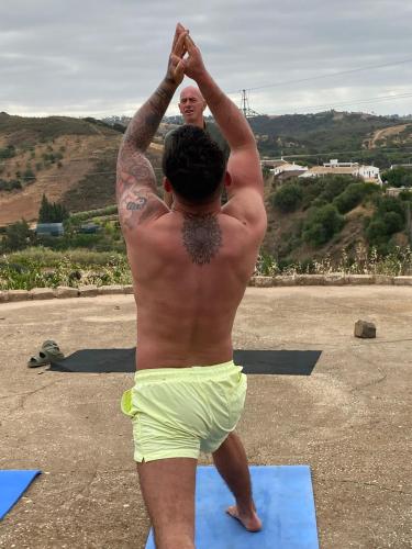 a man in yellow shorts doing a yoga pose at Yoga Farm in Tavira