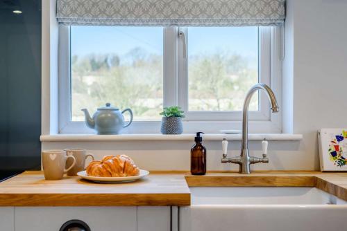 un fregadero con un plato de pan y una ventana en Hillcrest Cottage, en Avening