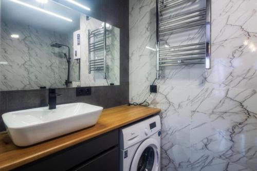 a bathroom with a sink and a washing machine at A-Y Apartments P A4 in Tbilisi City