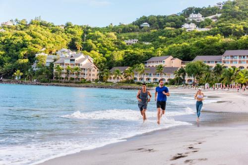 a group of people walking on the beach at BodyHoliday St Lucia in Gros Islet