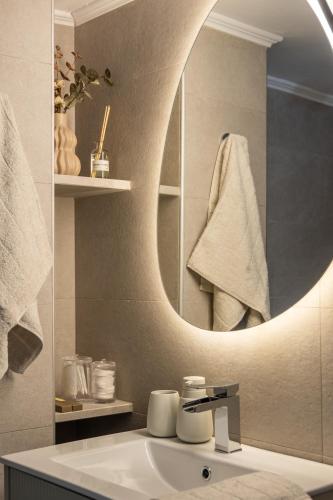 a bathroom with a sink with a round mirror at Melian Roots Apartment in Adamantas
