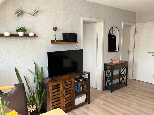 salon z telewizorem z płaskim ekranem w drewnianym centrum rozrywki w obiekcie Apartement Meerblick w mieście Wunstorf