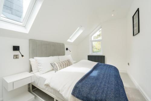 a white bedroom with a bed and a window at The Old Kiosk - Luxe 4 Bed House - Roath Park in Cardiff