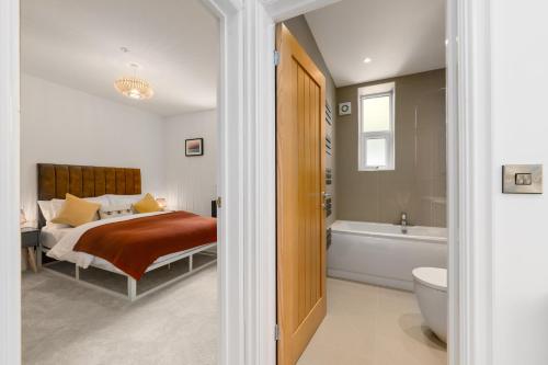 a bedroom with a bed and a bath tub at The Old Kiosk - Luxe 4 Bed House - Roath Park in Cardiff