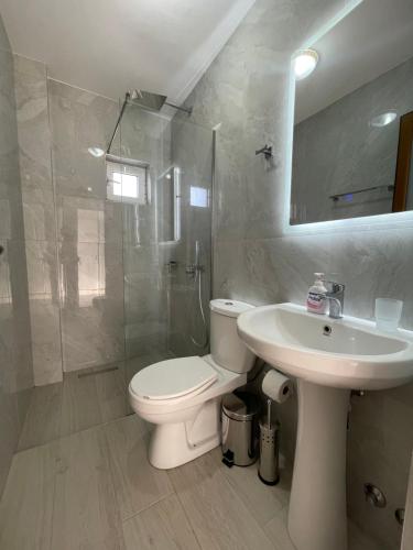 a bathroom with a toilet and a sink and a shower at Joni Apartments in Ksamil