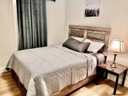 een slaapkamer met een bed en een tafel met een lamp bij New built home close to airport in Dieppe