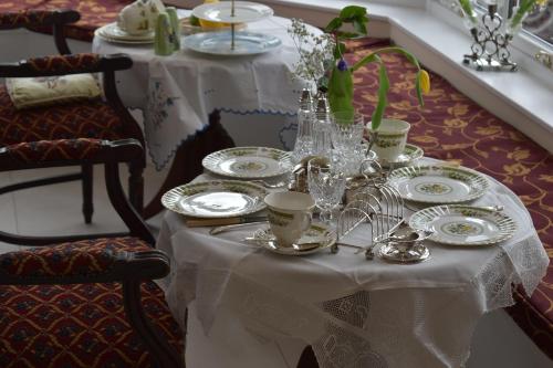una mesa blanca con platos y tazas y platos en ella en Tobervilla Guest House, en Caherdaniel