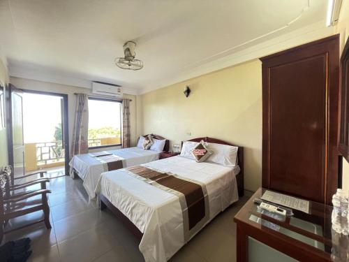 a hotel room with two beds and a window at Khách Sạn Huệ Vinh in Thương Xà (2)