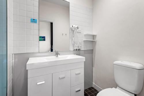 Baño blanco con lavabo y aseo en 1-Bed in CBD Perfect for a Melbourne City Break, en Melbourne