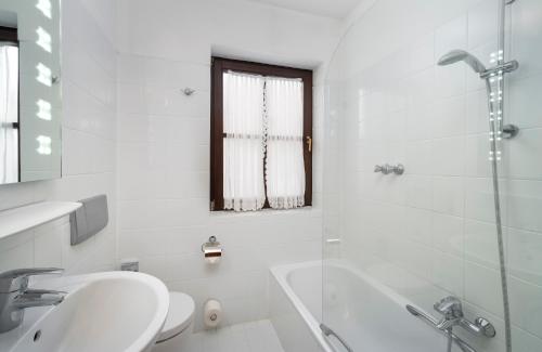 a white bathroom with a sink and a shower at ARKADEN Hotel Kelkheim in Kelkheim
